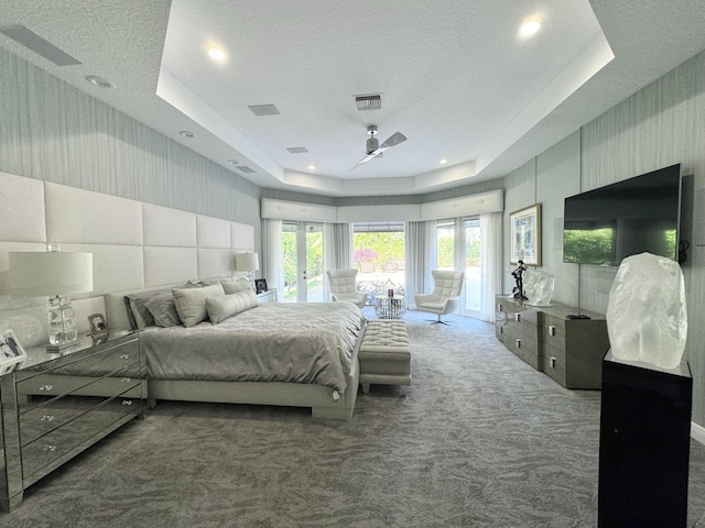 bedroom with a tray ceiling, access to exterior, carpet flooring, and a textured ceiling