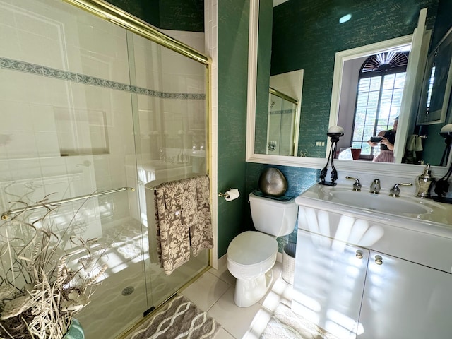 bathroom featuring tile patterned flooring, vanity, toilet, and a shower with shower door