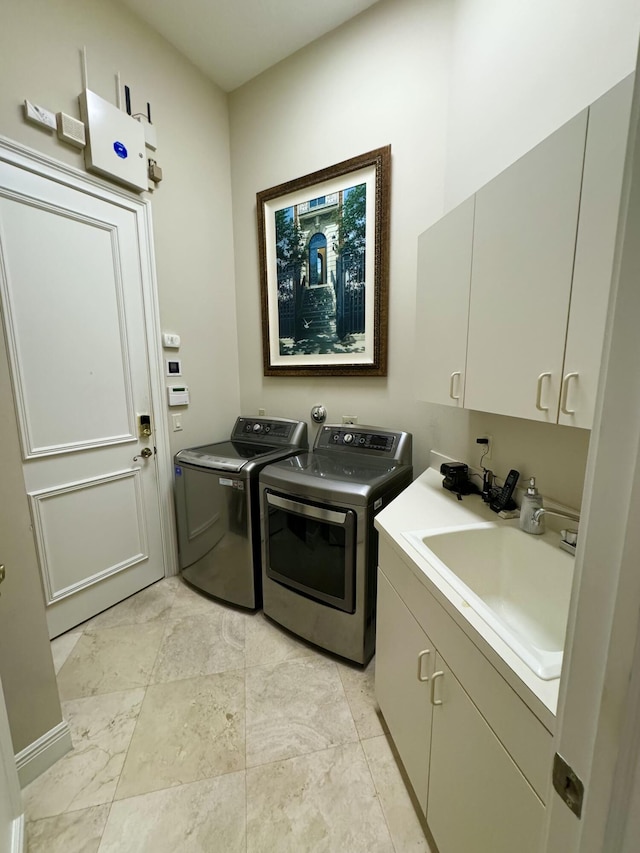 clothes washing area with separate washer and dryer, sink, and cabinets