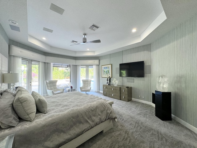 bedroom featuring a tray ceiling, ceiling fan, light colored carpet, and a textured ceiling