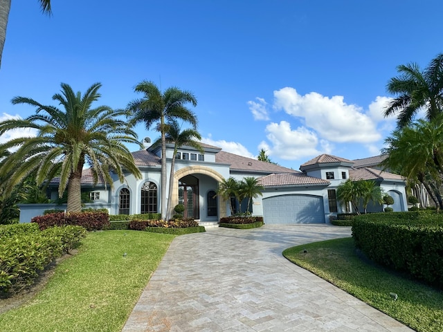 mediterranean / spanish house featuring a front yard and a garage