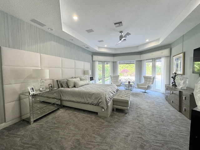 carpeted bedroom with a raised ceiling, access to exterior, a textured ceiling, and multiple windows