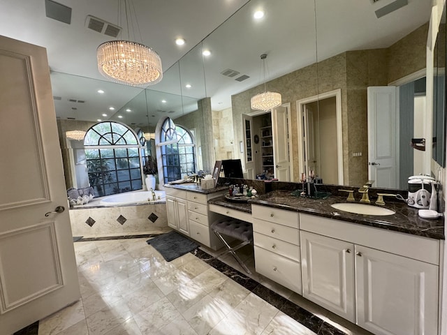 bathroom with a chandelier, vanity, and tiled tub