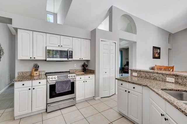 kitchen with stone countertops, light tile patterned flooring, white cabinetry, and appliances with stainless steel finishes