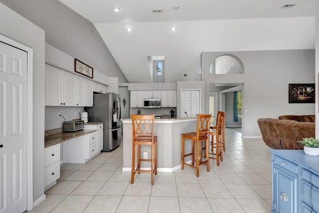 kitchen featuring appliances with stainless steel finishes, a center island, white cabinetry, and a kitchen breakfast bar