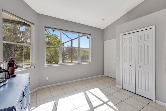 unfurnished bedroom featuring a closet, light tile patterned flooring, and vaulted ceiling