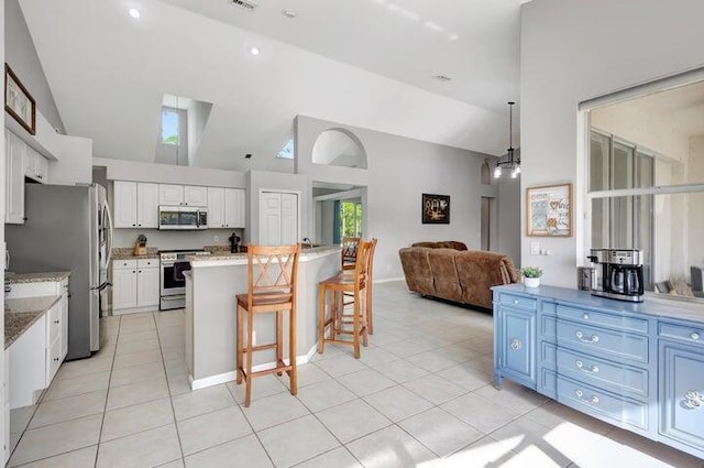 kitchen with stainless steel appliances, blue cabinets, light tile patterned floors, white cabinetry, and a breakfast bar area