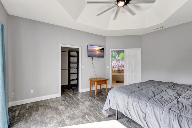 bedroom featuring a tray ceiling, connected bathroom, a spacious closet, and ceiling fan