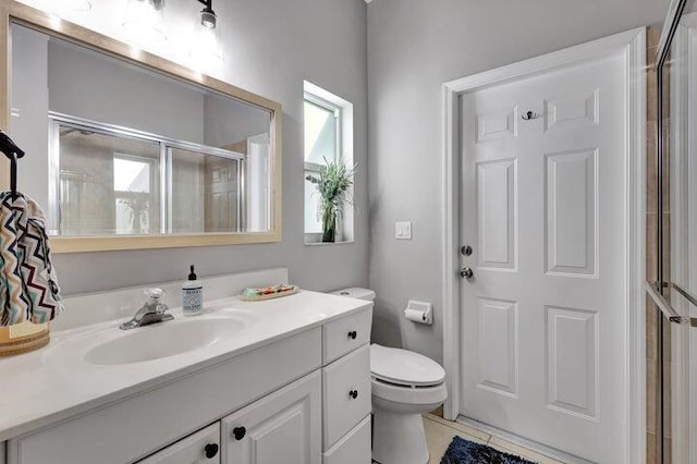 bathroom featuring tile patterned flooring, a shower with door, vanity, and toilet