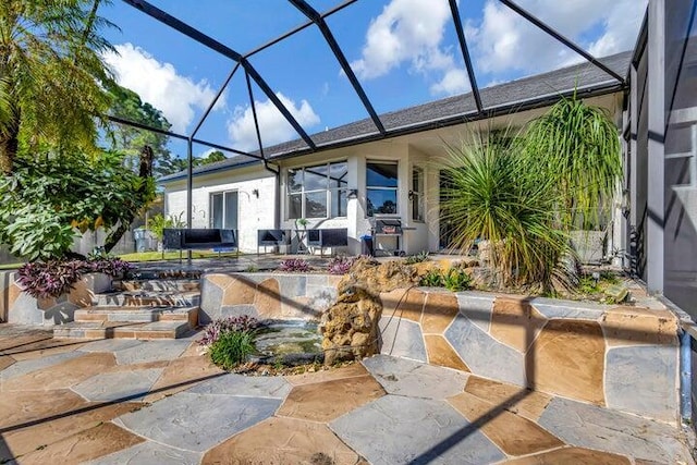 back of property featuring glass enclosure and a patio area