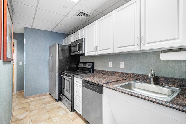 kitchen with a paneled ceiling, sink, light tile patterned flooring, white cabinetry, and stainless steel appliances