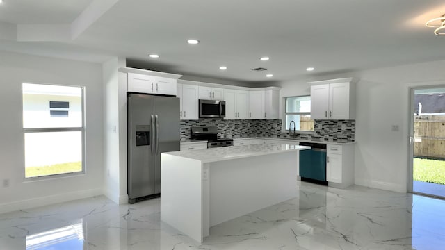 kitchen featuring a center island, sink, decorative backsplash, white cabinets, and appliances with stainless steel finishes