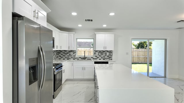 kitchen featuring white cabinets, a kitchen island, sink, and stainless steel appliances