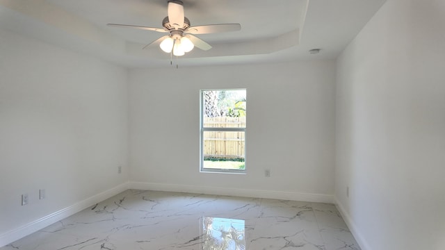 spare room featuring a raised ceiling and ceiling fan