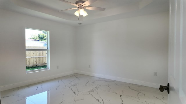 unfurnished room with ceiling fan and a raised ceiling