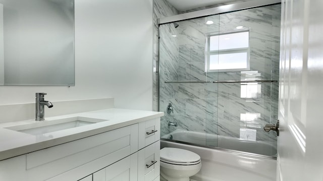 full bathroom featuring combined bath / shower with glass door, vanity, and toilet