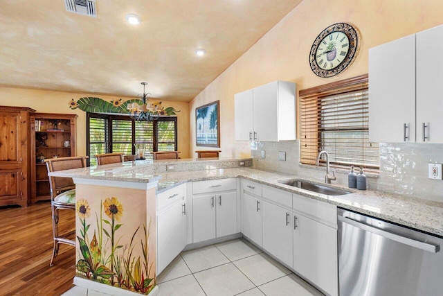 kitchen with dishwasher, a breakfast bar, white cabinets, sink, and kitchen peninsula