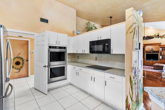 kitchen with white cabinetry, light stone counters, high vaulted ceiling, light tile patterned floors, and black appliances