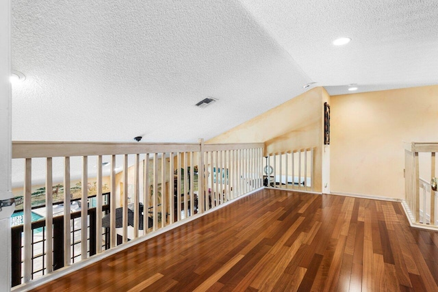 interior space with a textured ceiling, wood-type flooring, and lofted ceiling