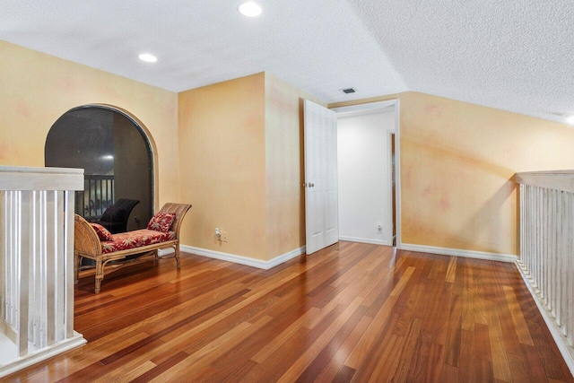 sitting room featuring wood-type flooring, a textured ceiling, and vaulted ceiling