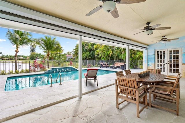 view of pool featuring french doors, pool water feature, ceiling fan, a water view, and a patio