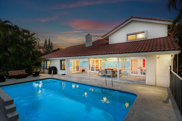 pool at dusk with a patio and french doors