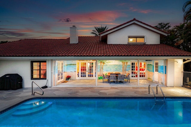 back house at dusk with a patio and french doors