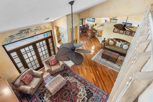 living room featuring a textured ceiling, ceiling fan, lofted ceiling, and hardwood / wood-style flooring