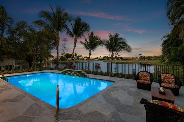 pool at dusk featuring a patio area and a water view