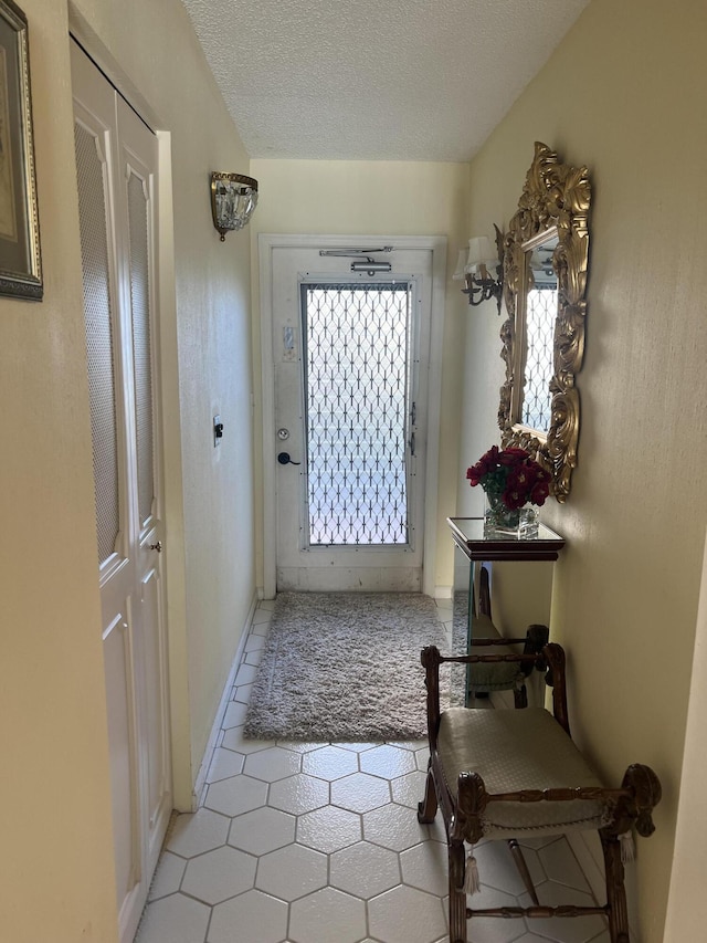 entryway with light tile patterned flooring, a textured ceiling, and baseboards