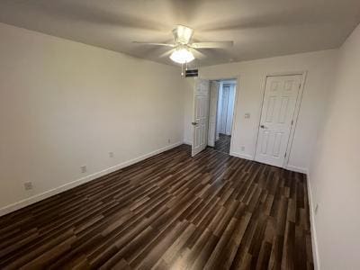 unfurnished bedroom with ceiling fan and dark wood-type flooring