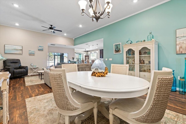 dining space with ceiling fan with notable chandelier, crown molding, and dark wood-type flooring