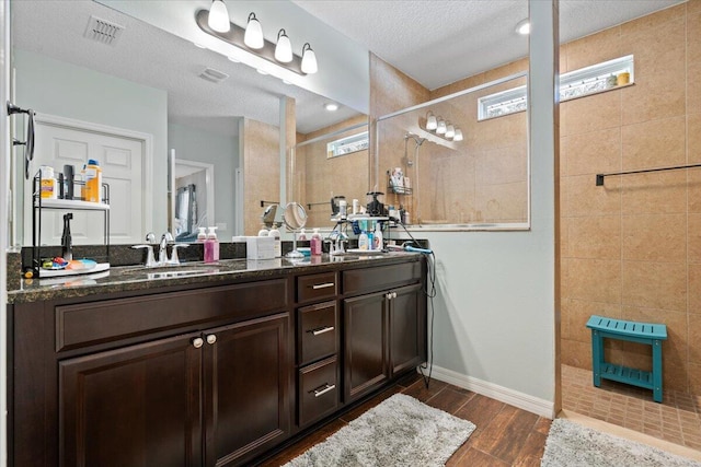 bathroom featuring a tile shower, vanity, and a textured ceiling