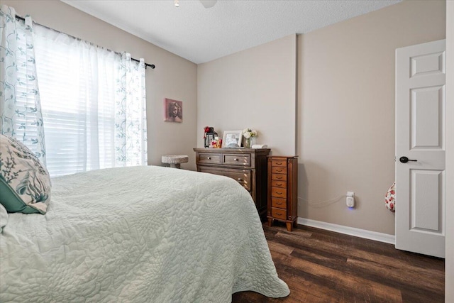 bedroom featuring dark hardwood / wood-style floors, ceiling fan, and a textured ceiling