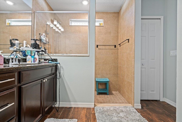 bathroom with a tile shower and vanity