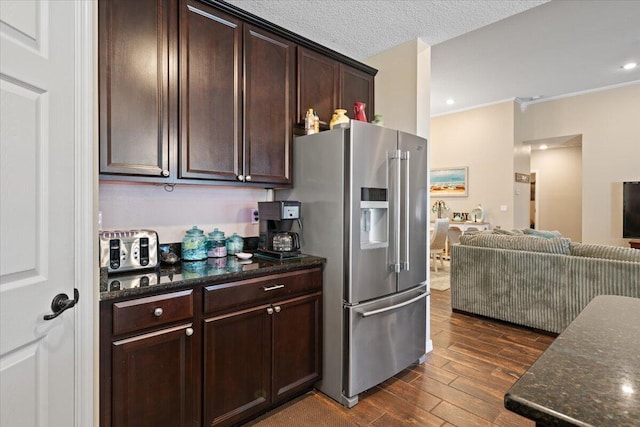 kitchen with dark stone counters, ornamental molding, a textured ceiling, high quality fridge, and dark brown cabinetry