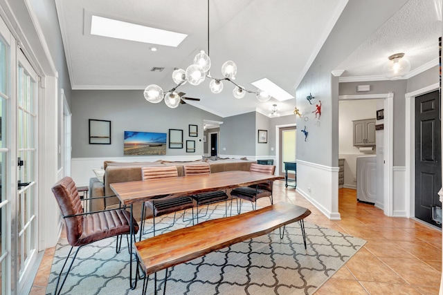 tiled dining space with a textured ceiling, ceiling fan, crown molding, and vaulted ceiling with skylight