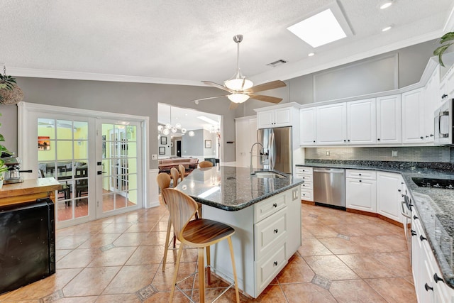 kitchen featuring ceiling fan with notable chandelier, white cabinetry, stainless steel appliances, and an island with sink