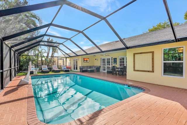 view of pool with outdoor lounge area, a patio, and glass enclosure