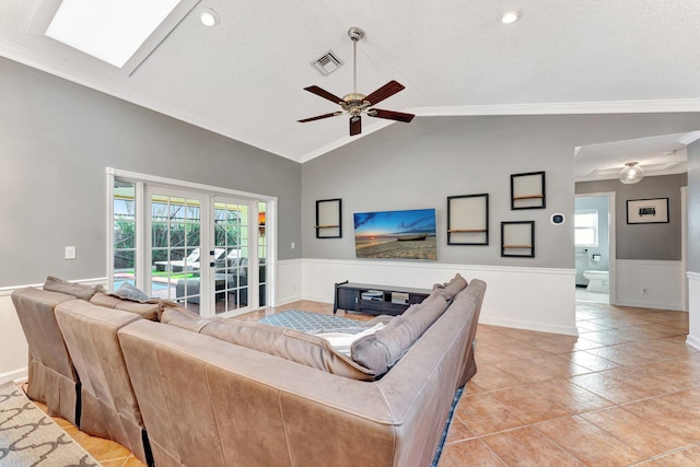 living room featuring ceiling fan, french doors, lofted ceiling with skylight, crown molding, and a textured ceiling