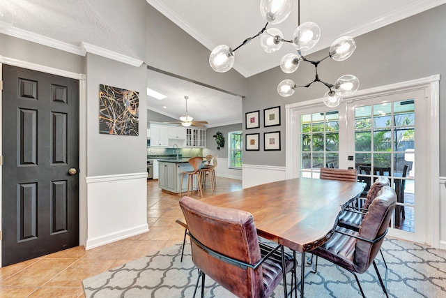 tiled dining space featuring sink, ceiling fan with notable chandelier, vaulted ceiling, and ornamental molding