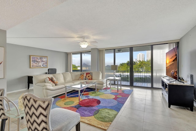 tiled living room featuring ceiling fan, floor to ceiling windows, and a textured ceiling