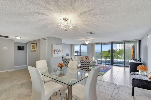 dining area with a wealth of natural light, ceiling fan with notable chandelier, a textured ceiling, and a wall of windows