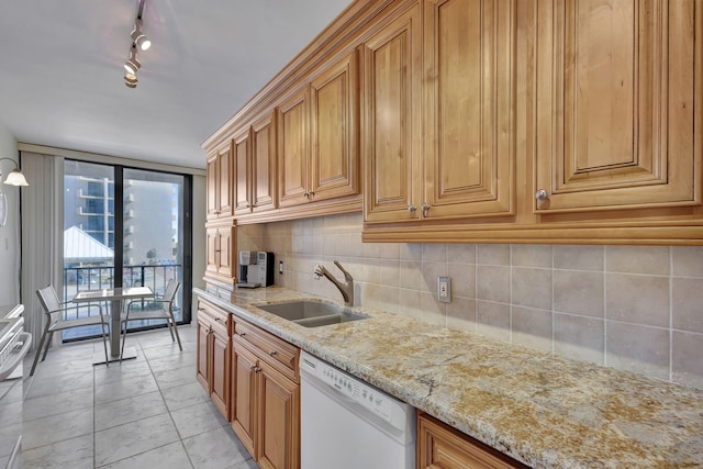 kitchen featuring decorative backsplash, light stone counters, white dishwasher, sink, and light tile patterned floors