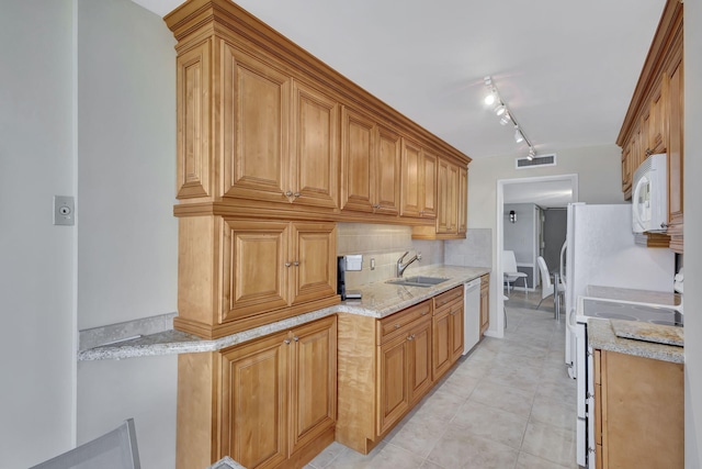 kitchen with white appliances, rail lighting, sink, decorative backsplash, and light stone counters