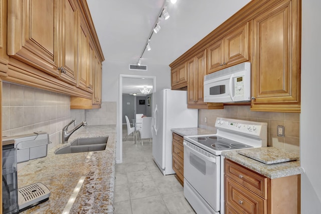 kitchen featuring tasteful backsplash, light stone counters, white appliances, sink, and an inviting chandelier