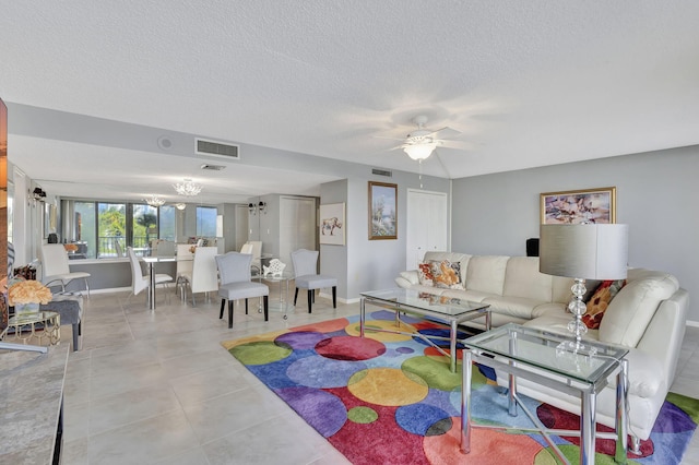 living room with ceiling fan, light tile patterned floors, and a textured ceiling