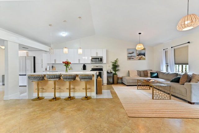 kitchen featuring appliances with stainless steel finishes, decorative light fixtures, white cabinetry, a kitchen island, and a breakfast bar area