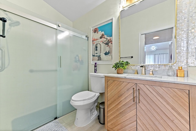 bathroom with a shower with door, vanity, vaulted ceiling, and toilet