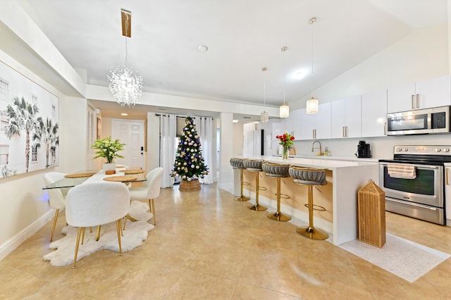 kitchen with white cabinets, appliances with stainless steel finishes, a kitchen island with sink, and pendant lighting